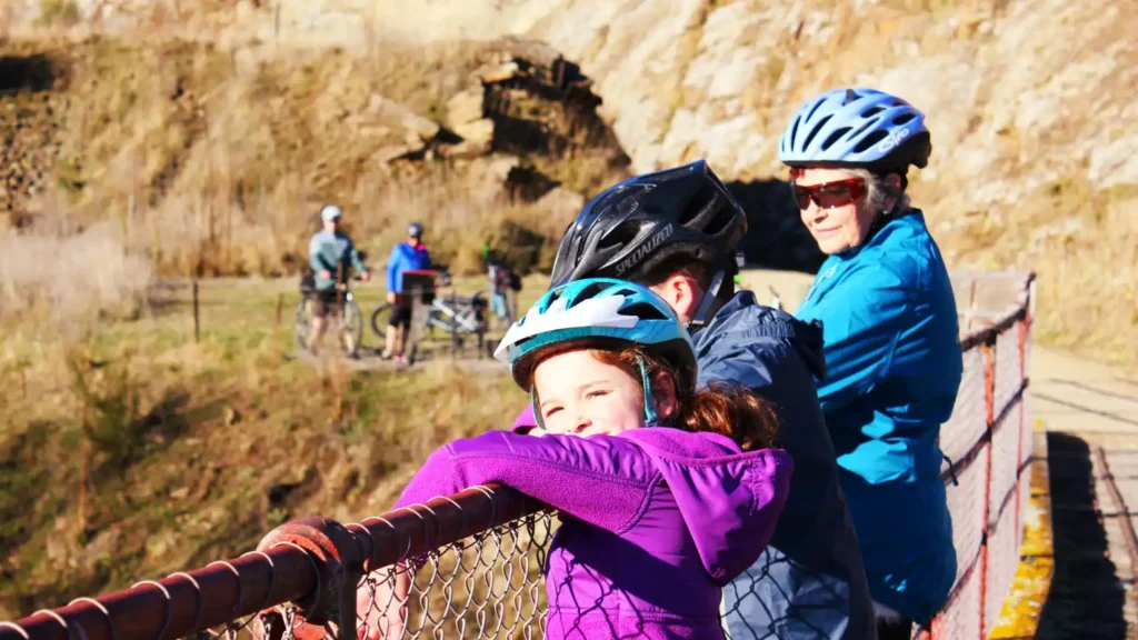 A young girl and her family looking down at the river near the Poolburn Gorge section of the Otago Central Rail Trail with shebikeshebikes